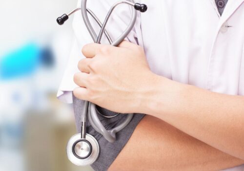 A visual of a doctor with their arms folded holding a stethoscope.