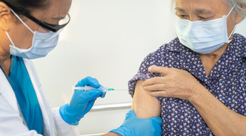 Patient receiving a vaccination, the patient and clinician are both wearing face masks.