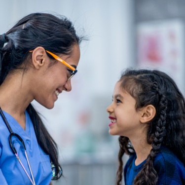 Child smiling with a doctor at an appointment.
