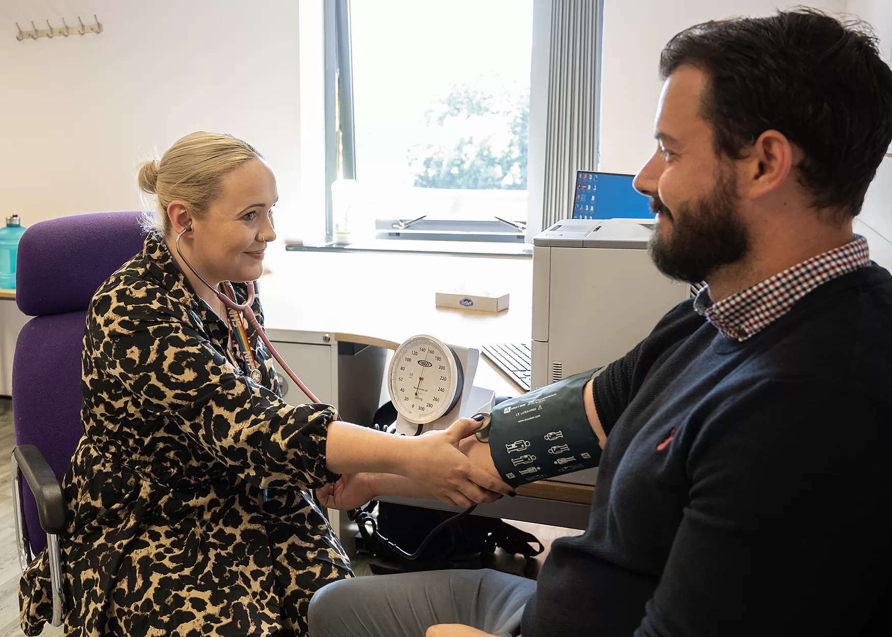 Patient receiving a blood pressure check by a GP assistant.