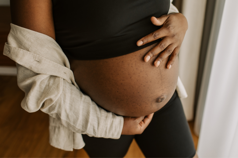 Close up of a pregnant person cradling their stomach.