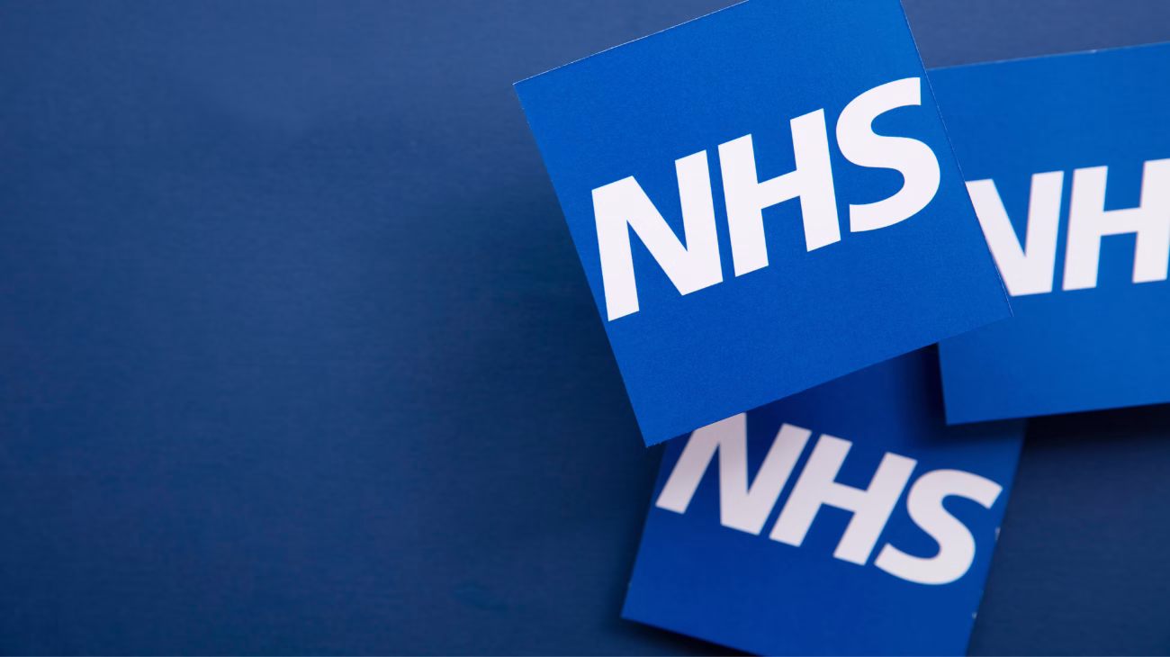 Three NHS logos (the letters NHS in a blue square) pictured against a dark blue background.