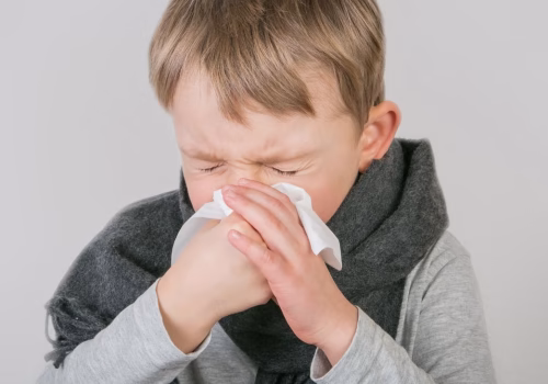 Image of a child sneezing into a tissue