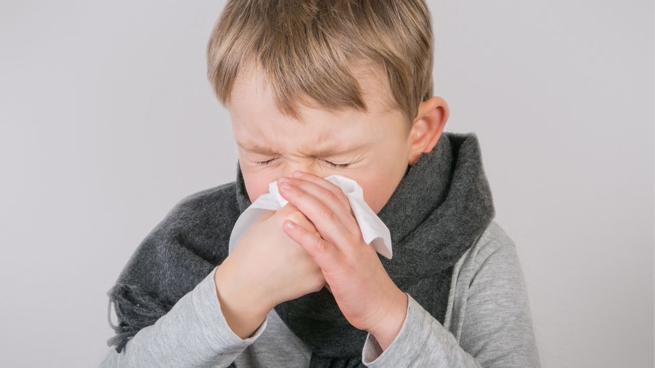 Image of a child sneezing into a tissue