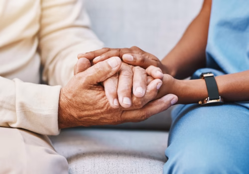 A person and a carer holding hands