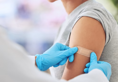 Young person having a plaster put on their arm after having a vaccine.