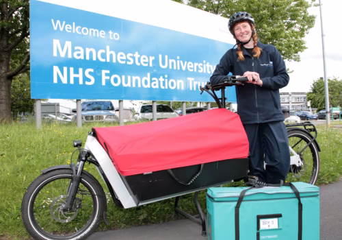 Manchester University NHS Foundation Trust site. A person on a E-cargo bike.