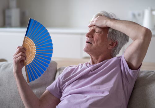 a person sat on a sofa using a fan to cool down