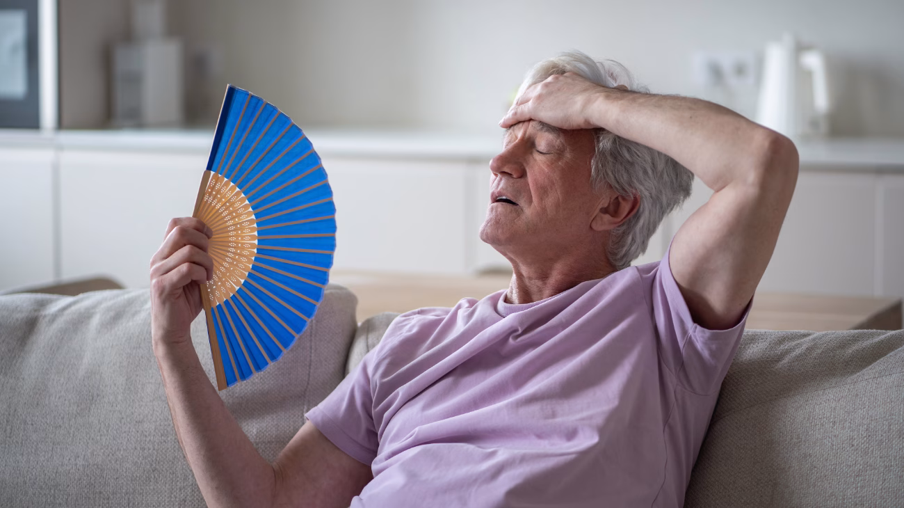 a person sat on a sofa using a fan to cool down