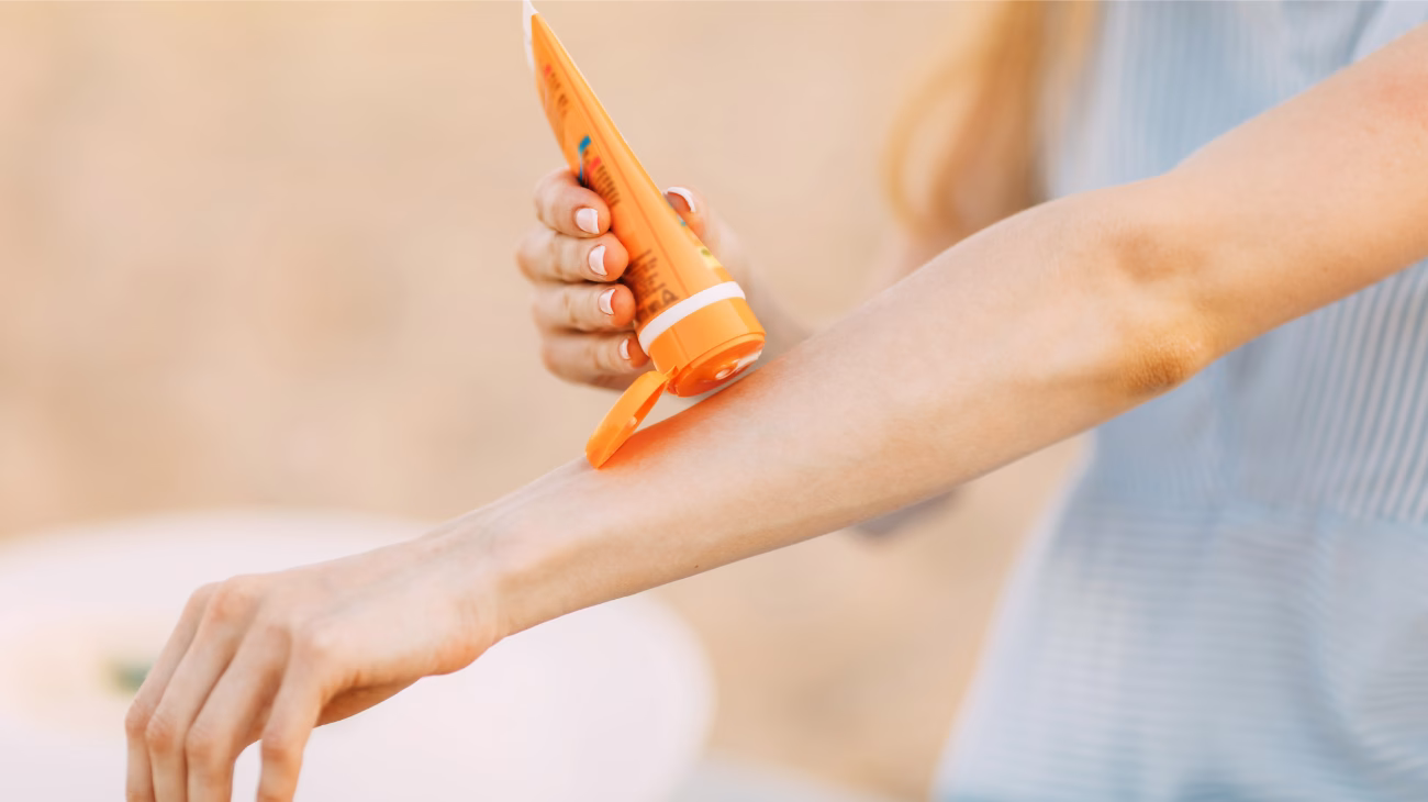 person applying sun cream to arm