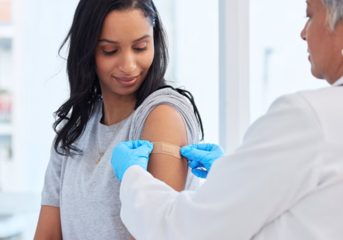 Clinician putting a plaster on a young persons arm where they got vaccinated